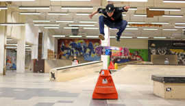 Ein Skateboarder hebt ab an einem Rail in einer Skatehalle 