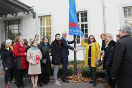 OB Wolfram Leibe und Frauenbeauftragte Angelika Winter ziehen die Terre des Femmes-Fahne vor dem Rathaus hoch.