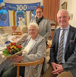 Klara Tschickardt sitzt mit einem Blumenstrauß am Geburtstagstisch. Neben ihr sitzt OB Wolfram Leibe, hinter ihr steht Doris Steinbach.