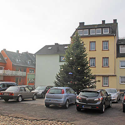 Etwas verloren wirkt der Weihnachtsbaum zwischen den Autos auf der rissigen Asphaltdecke des Platzes an der Numerianstraße in Euren.