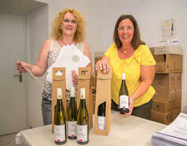 Monika Mischtian (links) und Erika Dahlem vom städtischen Protokollreferat präsentieren den neuen OB-Wein und die Urkunden, die ab dem 100. Geburtstag sowie bei Ehejubiläen überreicht werden.