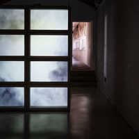 In einem abgedunkelten Ausstellungsraum steht eine Wand aus Betonquadern, die den Blick freigibt auf die Projektion eines Himmels. 