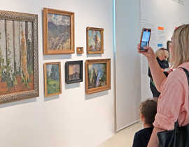 Eine Besucherin macht mit dem Smartphone einen Schnappschuss ihres Lieblingsobjekts in der Ausstellung „Tell Me more“.