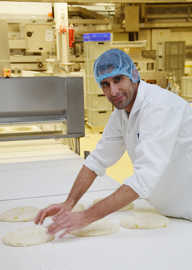 Der aus Afghanistan stammende Flüchtling Ezat Khwaja bearbeitet einen Kuchenteig in der Großbäckerei Biebelhausener Mühle.