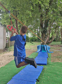 Ein Kind in blauer Sportkleidung hängt an einer Seilrutsche