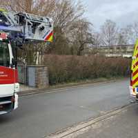 Das Bild zeigt ein Feuerwehrfahrzeug mit Leiter und einen Rettungswagen. Sie stehen vor einer Hecke. Dahinter ist ein Bungalow zu sehen.
