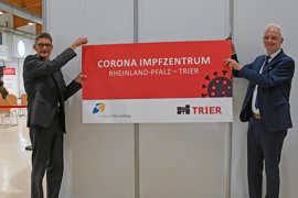 Kurz vor der Schließung hängen Landrat Günther Schartz (links) und Oberbürgermeister Wolfram Leibe symbolisch die Beschilderung des gemeinsam betriebenen Impfzentrums ab.