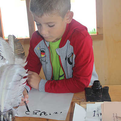 Der siebenjährige Maximilian Müller ist das erste Mal in der Spielstadt und schreibt konzentriert eine Urkunde mit der Feder.