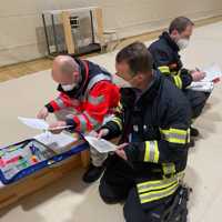 Einsatzkräfte von Rettungsdienst und Feuerwehr vergleichen Dokumente.