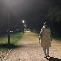 Eine Frau von hinten, die nachts einen erleuchteten Weg entlangläuft