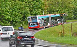 Ein Bus fährt eine Steigung hoch, gefolgt von mehreren Autos