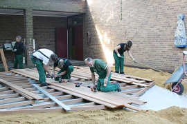 Mitarbeiter der Bitburger Braugruppe bauen im Rahmen von TAT ein Podest auf dem Grundstück der Kita 'Haus für Kinder' in der Krahnenstraße.