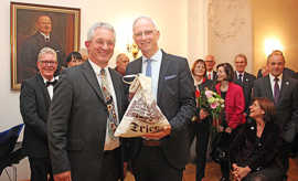 Aloys Hülskamp (l.) überreicht Wolfram Leibe eine Tasche mit hilfreichen Gegenständen für dessen verbleibende Amtszeit als Oberbürgermeister.