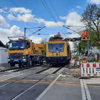 Arbeiten mit einem gelben Schienenfahrzeug und eine LKW an den Oberleitungen einer Eisenbahnstrecke
