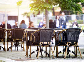 Leere Stühle an einem sonnigen Tag auf einer Außenterrasse eines Lokals