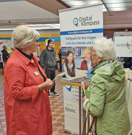 Zwei ältere Frauen im Gespräch an einem Messestand