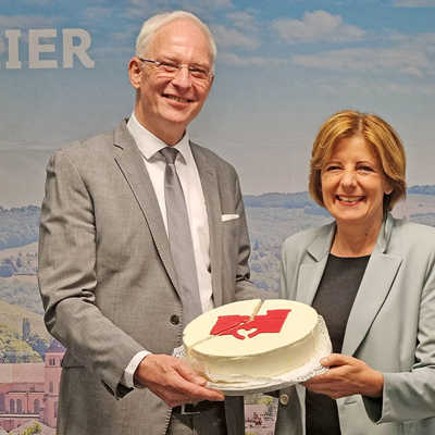 OB Wolfram Leibe zeigt Ministerpräsidentin Malu Dreyer lächelnd an einem Kuchen, welch großen Schuldenberg das Land nun Trier abnimmt: Es sind rund 266 Millionen Euro, was etwa zwei Drittel der Schulden durch Liquiditätskredite entspricht.