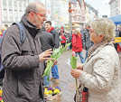 Zum Start der Aktionstage „Wir für Demokratie“ überreicht Thomas Zuche (Caritas) einer Passantin auf dem Hauptmarkt eine Frühlingsblume mit Info-Flyer.