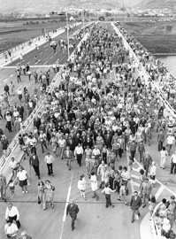 Das Schwarz-Weiß-Bild zeigt aus der Vogelperspektive eine große Menschenmenge, die über eine Straßenbrücke spaziert