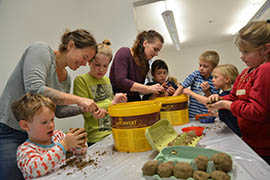 Fleißig bauen die Kinder unter Anleitung von Caroline Liebscher vom Grünflächenamt (4. v. l.) die „Saatbomben“, also Lehmkugeln, die mit Samen gefüllt sind.