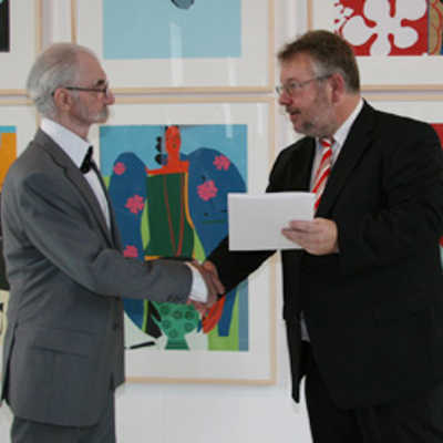 Kulturdezernent Ulrich Holkenbrink (rechts) gratuliert Dieter J. J. Sommer zur Verleihung des Ramboux-Preises 2008. Im Hintergrund mehrere Arbeiten des Trierer Künstlers aus der Serie „Ikea-Girl“.