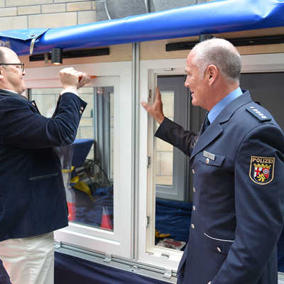 Unter dem wachsamen Blick von Hauptkommissar Michael Lui versucht sich Ordungsdezernent Ralf Britten am Aufhebeln eines Fensters mit einem Keil.