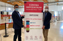 Wolfram Leibe und Günther Schartz werben mit einem Plakat für einen Besuch im Impfzentrum