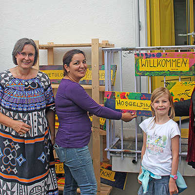 Bürgermeisterin Angelika Birk (r.) und Kita-Leiterin Dagmar Denés (2. v. l.) bringen gemeinsam mit Kindern und Eltern Willkommensschilder an.