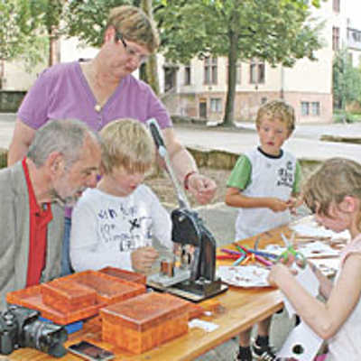 Unter der Anleitung von Sabine Berg (hinten Mitte) produziert ein „Rathaus Kid“ einen bunten Button für Oberbürgermeister Klaus Jensen (l.). Bei gutem Wetter finden viele Kreativangebote auf dem Hof der Barbara-Grundschule statt.