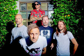 Bandfoto der fünf Donots vor einem mit Efeu umrankten Fenster