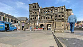 Blick auf die Porta Nigra aus der Froschperspektive mit dem Pflasterbelag des Vorplatzes im vordergrund.