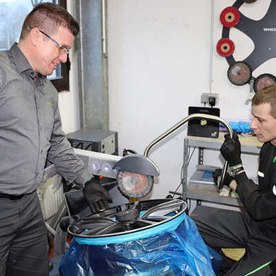 Eigens für den neuen Arbeitsbereich von Philipp Mayer (rechts) hat Thorsten Hoffmann ein Reparaturgerät für Autofelgen angeschafft. Sein neuer Mitarbeiter wurde speziell dafür weitergebildet. Foto: Jobcenter