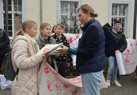 Zwei Schülerinnen überreichen der Bundestagsabgeordneten Corinna Rüffer rote Handabdrücke als Zeichen des Protests gegen Kindersoldaten.