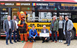 Vor dem Stadtbus im WM-Design werben Maskottchen „Hanniball“ und Sportdezernent Andreas Ludwig (4. v. r.) für das Kombiticket, das als Eintrittskarte und Fahrschein im ÖPNV gilt.