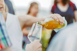 Weißwein wird aus einer Flasche in ein Glas gefüllt