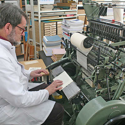 Buchbinder Edy Willems arbeitet in seinem Atelier in Zewen an einer Fadenheftmaschine, an der er alte Buchseiten zusammenheftet. Foto: Jan Söfjer