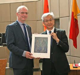 OB Wolfram Leibe übergibt dem stellvertretenden Bürgermeister von Nagaoka, Tatsunobu Isoda, eine Grafik des Trierer Doms
