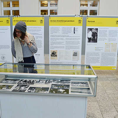 Besucherin Leja Büschges schaut sich Fotos in einer Vitrine an, die die zusammenfassenden Darstellungen der Schautafeln im Hintergrund ergänzen. Foto: Martin Seng