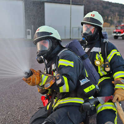 Zwei Feuerwehrmänner üben mit einem Hohlstrahlrohr.