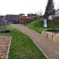 Weg durch einen Spielplatz mit Rasen, im Hintergrund ein Klettergerüst