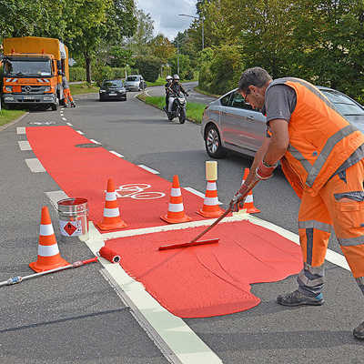 Ein Mitarbeiter der Firma Meiser Fahrbahnmarkierung aus Quierscheid verteilt frische Farbe über eine Radverkehrsfurt in der Hans-Böckler-Allee.