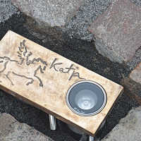 Bronzeplatte im Straßenpflaster mit Lampe, der Aufschrift "Katja" und einem stilisierten Pferd.