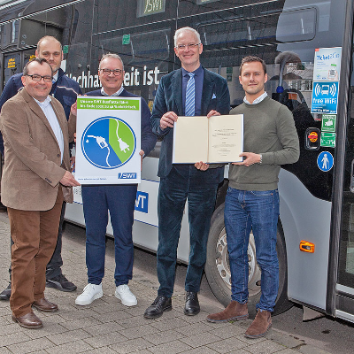 Elmar Kandels, Thomas Hüser und Arndt Müller (SWT) präsentieren zusammen mit OB Wolfram Leibe und dessen Büroleiter David Natus (v. l.) die Förderurkunde und ein Werbemotiv für die E-Bus-Flotte.
