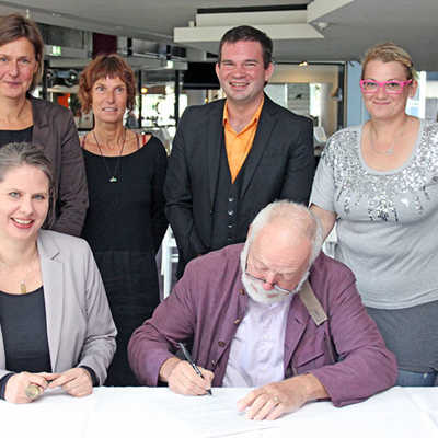 Dr. Klaus Reeh (Tufa, vorne r.) und Katharina John (Theater, vorne l.) unterzeichnen die Kooperationsvereinbarung. Mit ihnen freuen sich Teneka Beckers (Tufa, hinten l.), Christina Biundo (Kunstfähre, 2. v. l.), Marc-Bernhard Gleißner (Theater, 3. v. l.) und Krisztina Horvath (Theater, r.) auf viele spannende Projekte.