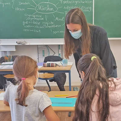 Lehramtsstudentin Janine Dieck bespricht mit zwei Schülerinnen aus der fünften Klasse eine Collage zum Thema Märchen im Deutschunterricht. 