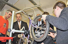 Oberbürgermeister Klaus Jensen schaut Schülern der Porta Nigra-Schule über die Schulter, die beim Trierer Engagementtag Fahrräder reparieren.