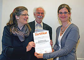Bürgermeisterin Angelika Birk und Rudolf Hahn, Leiter des städtischen Bildungs- und Medienzentrums, überreichen Melanie Rausch ihr Zertifikat.