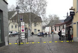 Blick aus der Glockenstraße auf den Platz Sieh um Dich an der Ecke Rindertanz- und Sichelstraße: Wie die Visualisierung zeigt, soll der Poller an dieser Stelle die Einfahrt in die Fußgängerzone außerhalb der Lieferzeiten versperren. Nähert sich ein Auto von „innen“, senkt sich der Poller automatisch ab. Abbildung: Tiefbauamt Visaulisierung der geplanten Anlage mit versenkbarem Poller in der Glockenstraße.