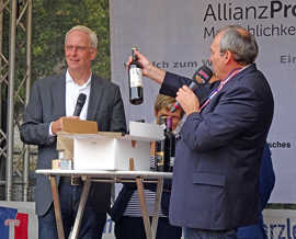 OB Wolfram Leibe, DRK-Vorstandsvorsitzende Anke Marzi (verdeckt) und Auktionator Thomas Vatheuer (v. l.) bringen Spitzenweine für den guten Zweck unter das Volk.