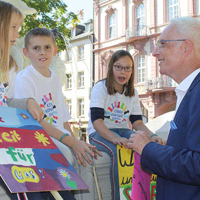 Kinder der Jugendkonferenz Ehrang, die ihre Demo-Plakate mitgebracht haben, befragen Oberbürgermeister Wolfram Leibe.